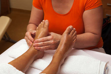 Woman receiving a leg and foot massage while lying on a towel in a awarded health massage center, series of various techniques の写真素材