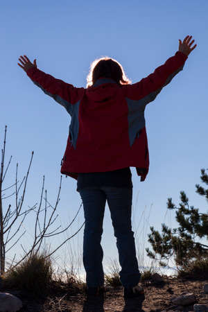 Silhouette of a woman catching the sun, against the clear blue sky, with the sun shining behind her