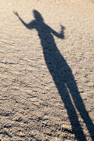 Long shadow of a woman performing Yoga, late afternoon, on the sandy beach の写真素材