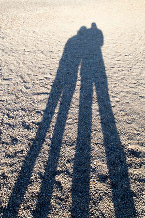 Long shadows of the couple on the sandy beach