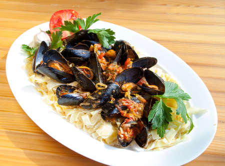Pasta with Mediterranean mussels in tomato sauce with fresh herbsの写真素材