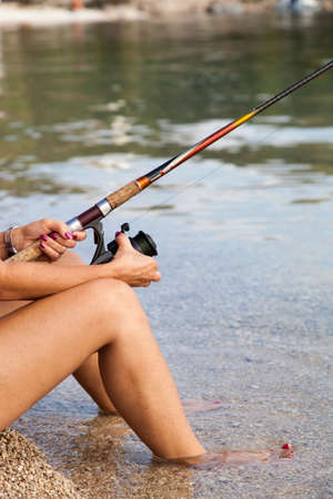 Pretty middle aged woman fishing on the sunny beachの写真素材