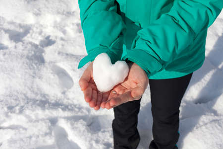 Female hands showing snow heart,  outdoor on a sunny winter day, Love concept. Valentine\\の写真素材
