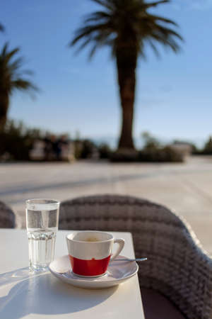 Coffee cup vacation relaxing concept, Coffee cup on the table, composition with palm in the background, selective focus on coffee cupの写真素材