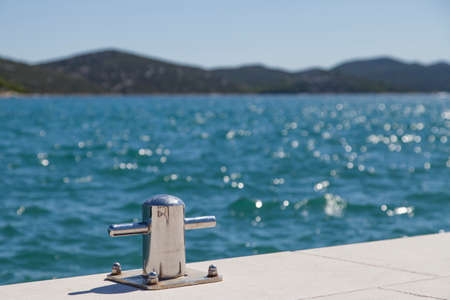 Metal mooring bollard on the dock of concrete harbor pier, selective focus on bollard, space for textの写真素材