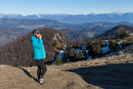 Pretty mid aged woman trekker woman putting balsam lips to repair her lips of the causes of winter cold high in mountains on sunny winter day, space for textの写真素材