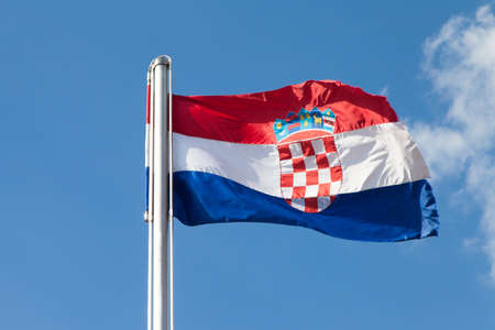 Croatian flag on a metal pole, fluttering in strong bora north-east wind, Sinj fortress, against blue sky, space for textの写真素材