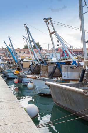Fishing boats and ships in the harbor, against blue skyの写真素材