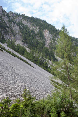 Scree is a slope of loose rock debris at the base of a steep incline or cliff, beautiful calm cloudy morning in Slovenian  Alps, Europeの写真素材