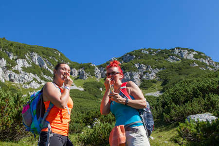 Mother and daughter eating sport power muesli bar, enjoying granola cereal bars, living healthy active lifestyle in mountain natureの写真素材