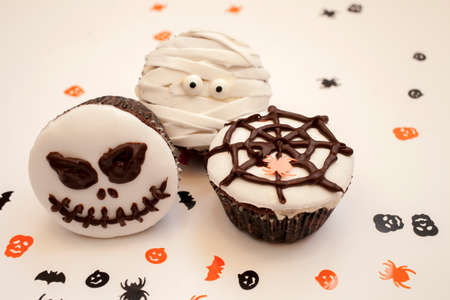 Home made Halloween spooky and creepy muffin cupcakes as a mummies, spider net and horror pumpkin, decorated with chocolate to Halloween party, on bright white background, selective focusの写真素材