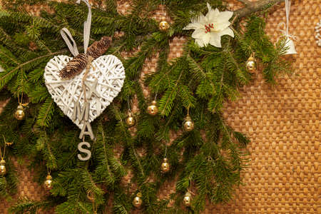 Christmas winter background decoration, natural pine evergreen branches with gold trinkets and XMAS letters on hand made heart, copy spaceの写真素材