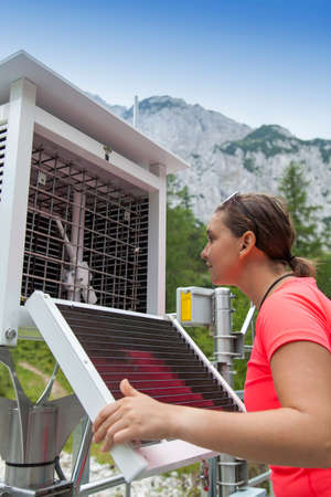 Pretty woman meteorologist reading meteodata instruments in modern meteorologic observation station, high in mountainsの写真素材