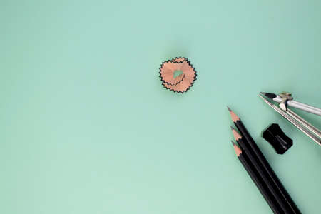 three black pencils along side a black sharpener and a pencil compass attached to a silver pencil pointing at a pink pencil shaving in the centerの写真素材