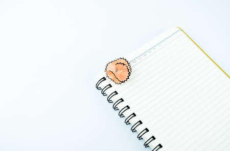 Some wooden pencil shaving over a white notebook on a white backgroundの写真素材