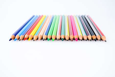 Top view of a line of some different colored wood pencil crayons arranged on a white backgroundの写真素材