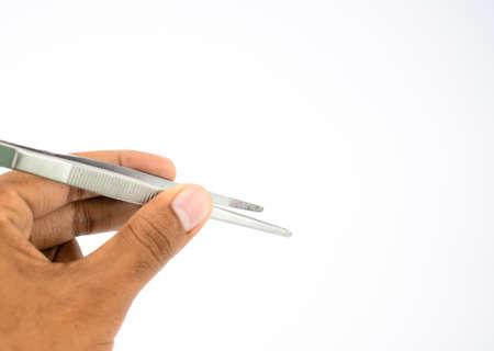 Close up picture of a person holding a tweezers in his hand in front of a white backgroundの写真素材