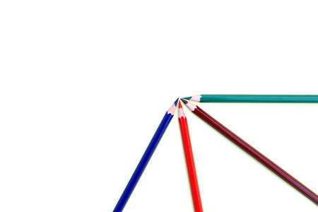 Four different colored pencil crayons arranged in a quarter circle on a light yellow paper backgroundの写真素材