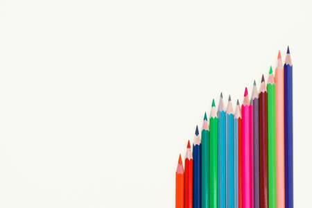 Different colored pencil crayons arranged in a row on an isolated white paper background
