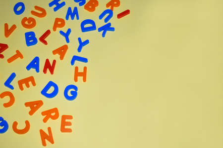 different colored letter blocks scattered over a single yellow paper background