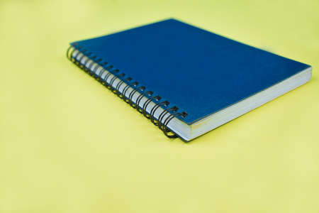 Side view picture of a completely blue colored normal diary before yellow paper background