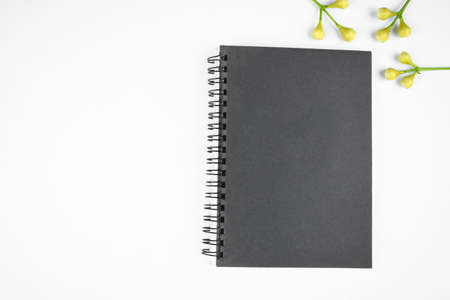 Simple gray colored paper diary and some small flowers before a bright white background