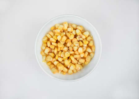 Delicious and fresh yellow sweet corn seed gathered in a white cup over an isolated white backgroundの写真素材