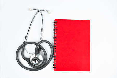 Photograph of a red diary and a stethoscope placed beside one another on an isolated white backgroundの写真素材