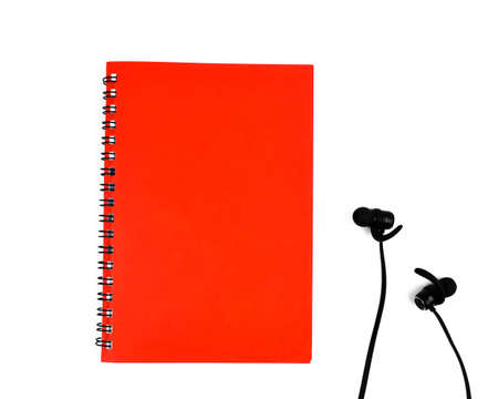 Black colored ear phone placed beside a single red colored note paper diaries before a white backgroundの写真素材