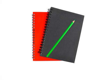 Top view of one green colored wood pencil crayon placed on top of two different colored note books before a white backgroundの写真素材