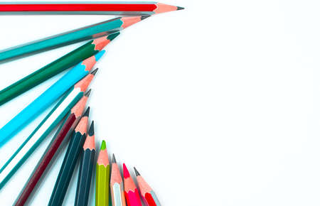 Different colored wood pencil crayons arranged in a half circle pattern on a white isolated...
