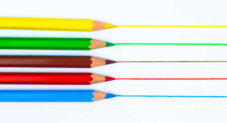 Drawing with five different colored pencil crayon on a white isolated backgroundの写真素材