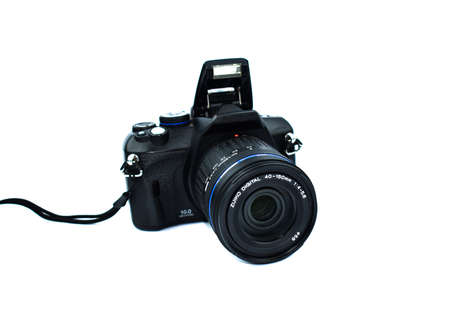 Dark black colored digital camera with lens attached to it placed on an isolated white background
