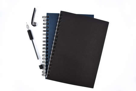 Bunch of blue and black colored note book diary and one black colored ball point pen placed together on a white backgroundの写真素材