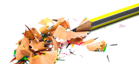 Yellow and silver color striped pencil crayons and some pencil shavings across a white isolated backgroundの写真素材