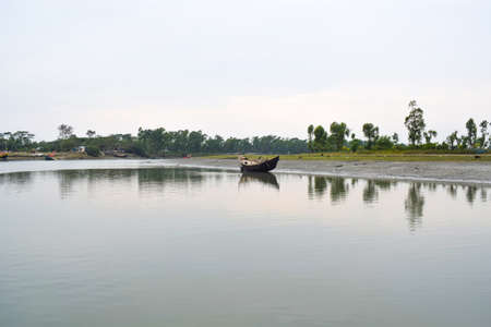 Small wooden boat which is block colored is going along a narrow river with freshの写真素材