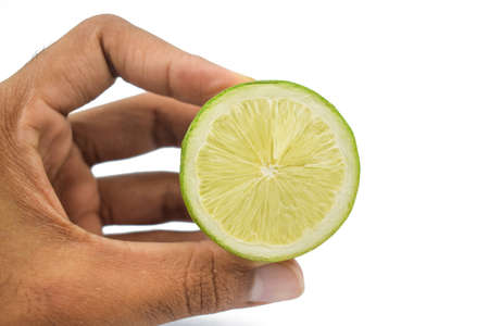 A person holding a half cut round and tasty lemon fruit gently in his hand with his fingerの写真素材