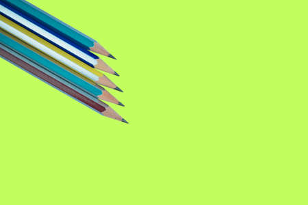 Some different colored wood pencil crayons arranged on a green paper backgroundの写真素材