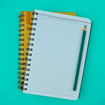 Green color wood pencil crayon placed on top of two note normal paper diariesの写真素材