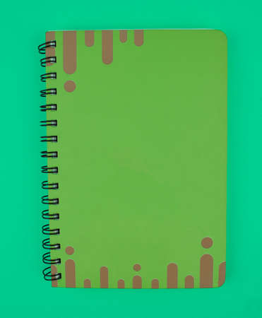 Green colored note paper diary placed on top of a light blue isolated paper backgroundの写真素材