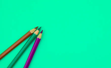 Three different color wood pencil crayons placed on top of a light blue paper backgroundの写真素材