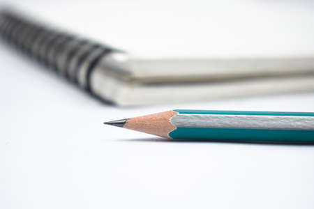 Blue color wood pencil crayon placed in front of a white colored note paper diaryの写真素材