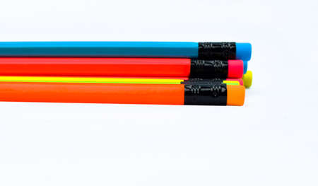 Some different colored wood pencil crayons placed beside one another on white paper background
