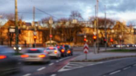Blurry un-focused abstract scene of an intersection with few cars and traffic lights. Cloudy sky in the evening above.の写真素材