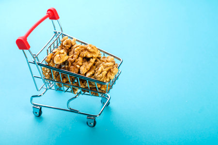 Food cart filled with peeled walnuts on a blue background. Copy space.の写真素材