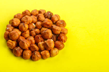 Peeled hazelnuts scattered on a yellow background.の写真素材