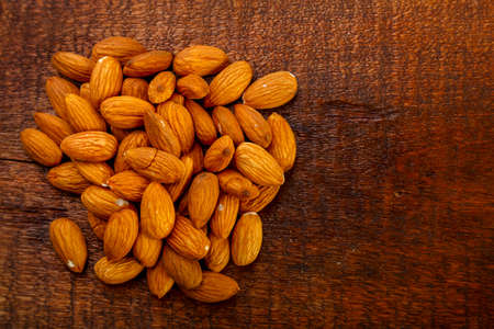 Almond nuts sprinkled on a square board on a wooden table.の写真素材