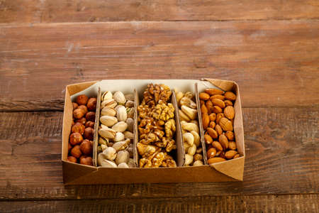 Assorted nuts in packaging on a brown wooden table. Copy spaceの写真素材