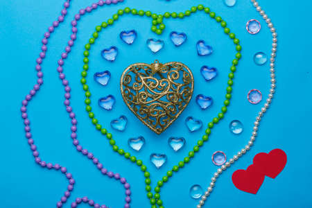 On a blue background, there is a heart of transparent pebbles in the shape of hearts in the middle...