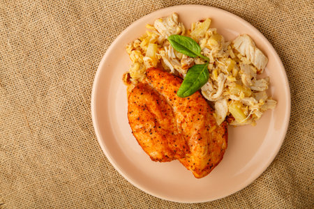 Baked chicken breast on a beige plate with pineapple salad. Horizontal photoの写真素材